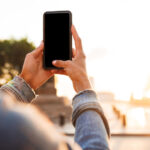 A young woman holding up her mobile phone